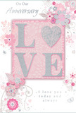 This anniversary card is captured in a close, detailed image, its design offering a gentle celebration of lasting romance that feels perfectly suited to a quiet evening in Brockley. The palette is soft and soothing: pastel pinks and muted silvery greys blend across the surface, creating a background that feels like a calm, overcast sky above spring blossoms. At the centre, the word LOVE is spelled out in softly raised glitter letters, each character defined yet delicate. The glitter is fine and evenly applied, giving a subtle shimmer rather than a bold sparkle. Where the O would normally be, a heart shape appears, rendered in shimmering silver with a slightly textured surface, making it the emotional focal point of the card. Around this word, delicate blooms in blush and mauve shades unfold with a watercolor softness, their petals and leaves formed from flowing, curved lines. The flowers and gentle vines loop around the centre, interspersed with tiny flourishes-small petals, swirling lines, and faint butterfly silhouettes that add movement, like the light rustle of leaves in nearby Brockley gardens. The background blush is smooth and even, lending warmth to the cooler silvery tones. Two key phrases, On Our Anniversary and I love you today and always, are written in a graceful, understated script, positioned so they feel naturally integrated into the composition. Subtle embossing and raised details suggest a tactile experience when held in hand. Overall, the card feels like a quiet whisper of affection, as personal and heartfelt as a handwritten note tucked into a bouquet delivered to a familiar doorstep off Brockley Road.